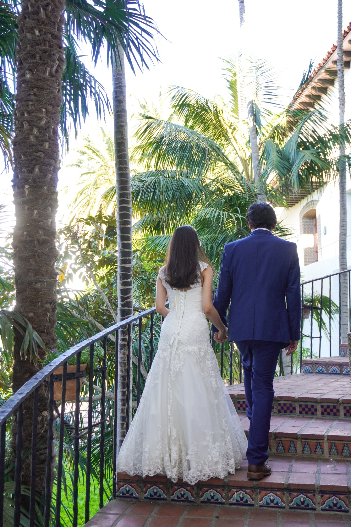 Bride and groom climbing tiled steps surrounded by palms at the Santa Barbara Courthouse