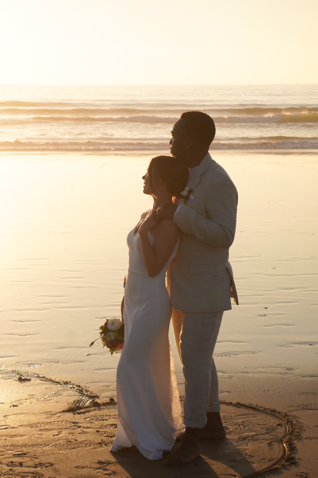 Oxnard, California beach wedding — couple embracing at sunset on Mandalay Beach with the Pacific Ocean behind them