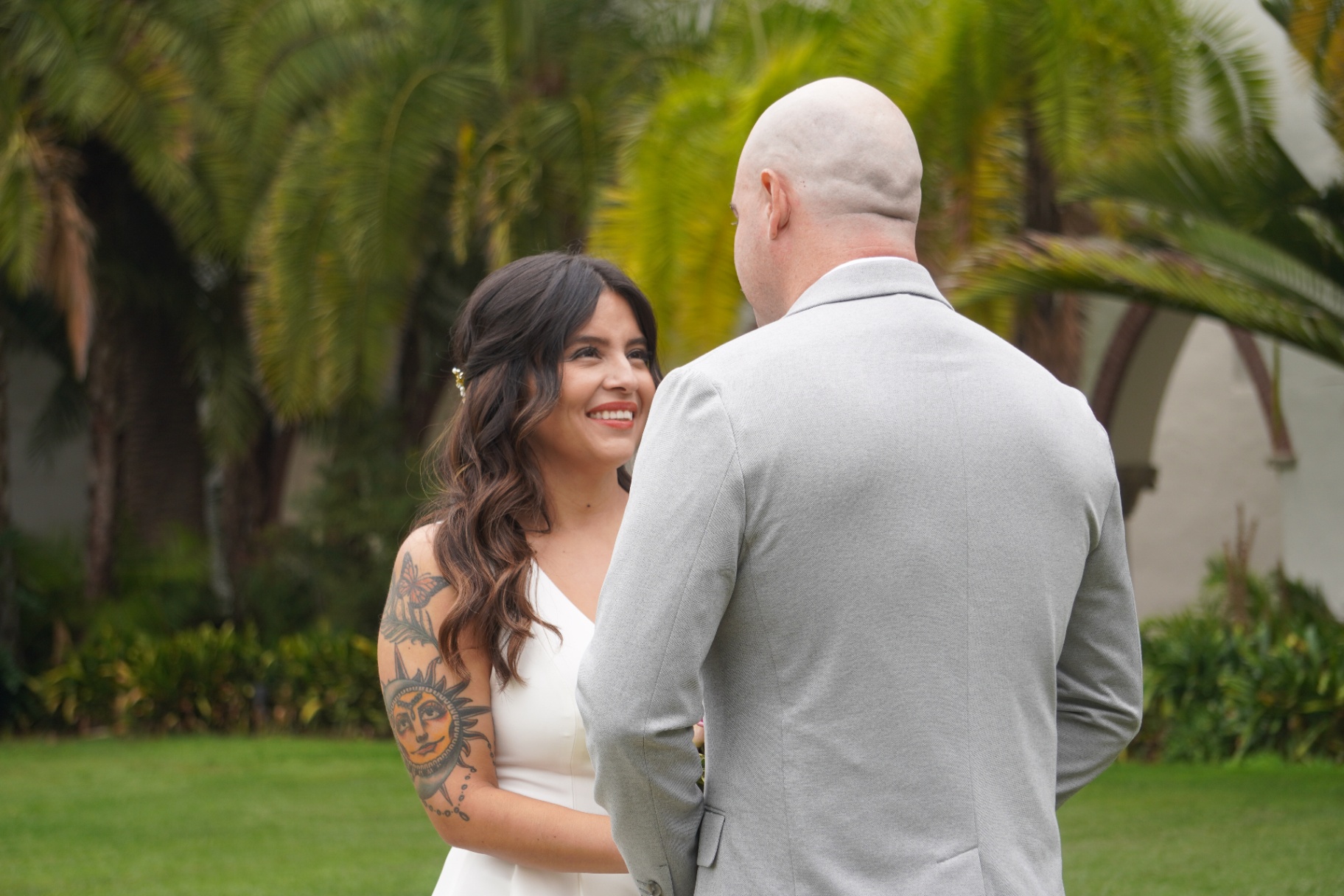 Smiling bride and groom sharing a first look in front of Spanish Colonial palms in Santa Barbara