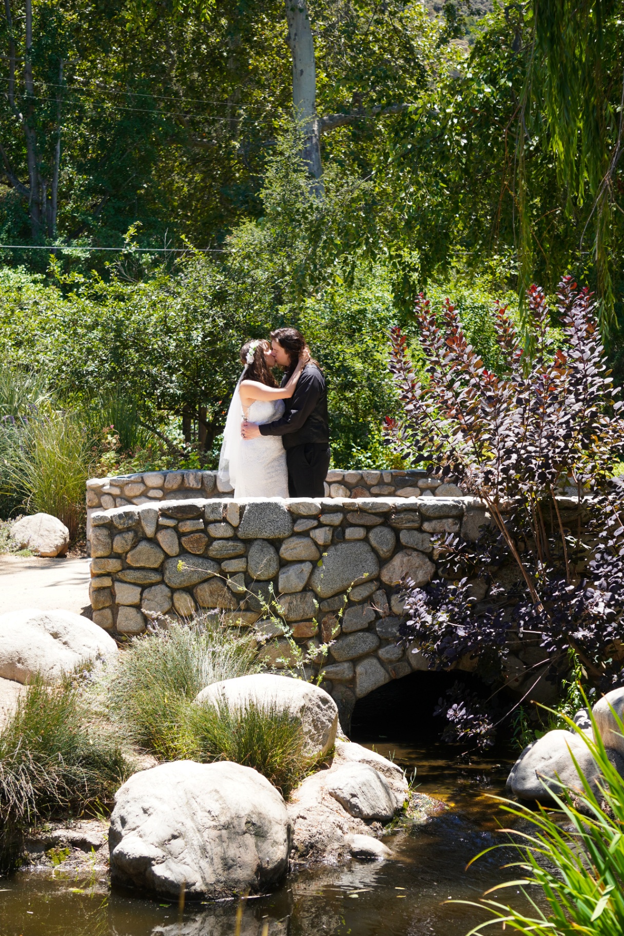 Los Angeles garden wedding couple kissing on a stone bridge surrounded by lush greenery