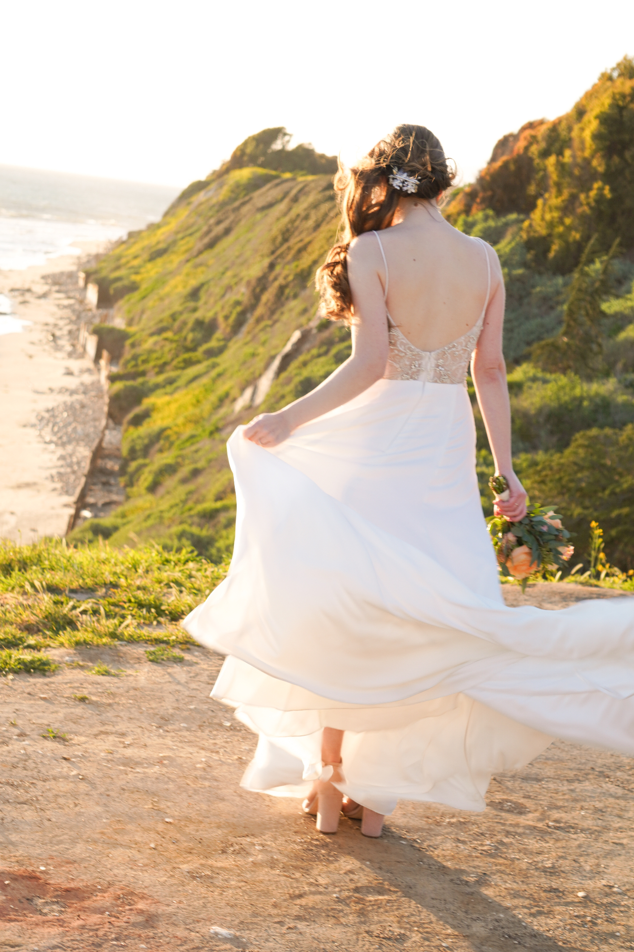 Bride in a flowing gown on a coastal bluff at golden hour above the Santa Barbara shoreline