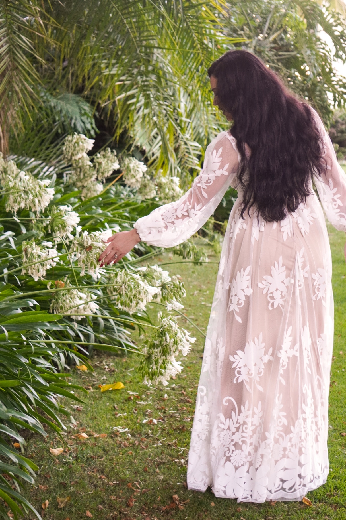Bride in a floral lace gown touching agapanthus blooms in a Santa Barbara garden